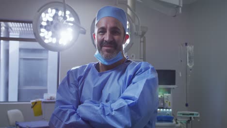 Porträt-Eines-Kaukasischen-Männlichen-Chirurgen-Mit-Gesenkter-Gesichtsmaske,-Der-Im-Operationssaal-Lächelt