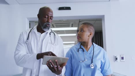 Afroamerikanischer-Männlicher-Arzt-Und-Weibliche-Gesundheitshelferin-Diskutieren-über-Ein-Digitales-Tablet-Im-Krankenhaus