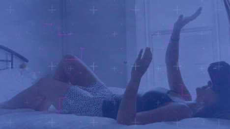 Light-trails-against-caucasian-woman-wearing-vr-headset-gesturing-while-lying-in-the-bed-at-home