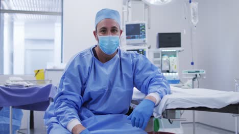 Retrato-De-Un-Cirujano-Caucásico-Con-Mascarilla-Sentado-En-El-Quirófano-Del-Hospital