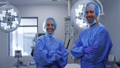 Portrait-of-smiling-female-and-male-caucasian-surgeons-with-face-masks-and-protective-clothing