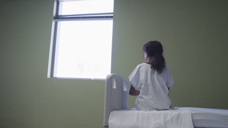 Mischlingsmädchen-Sitzt-Im-Krankenhausbett-Und-Schaut-Durch-Das-Fenster