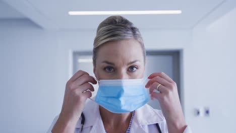Portrait-of-caucasian-female-doctor-putting-face-mask-on