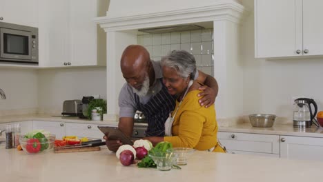Afroamerikanisches-älteres-Paar,-Das-Zu-Hause-In-Der-Küche-Einen-Videoanruf-Auf-Einem-Digitalen-Tablet-Führt