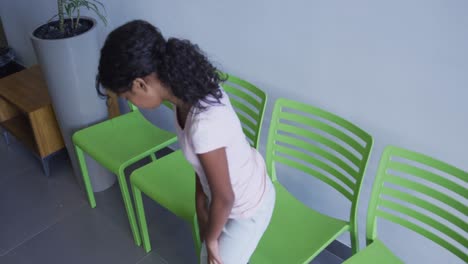 Afroamerikanisches-Mädchen-Sitzt-Auf-Einem-Stuhl-Im-Flur-Des-Krankenhauses