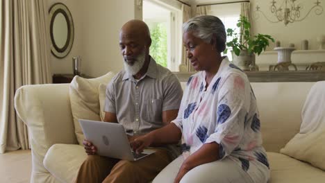 Afroamerikanisches-älteres-Paar,-Das-Gemeinsam-Einen-Laptop-Benutzt,-Während-Es-Zu-Hause-Auf-Der-Couch-Sitzt