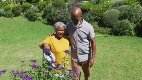 Afroamerikanisches-älteres-Paar-Lächelt,-Während-Es-Gemeinsam-Pflanzen-Im-Garten-Gießt