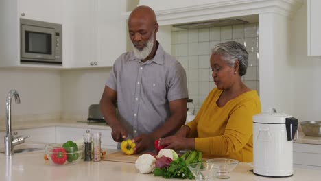 Afroamerikanisches-Seniorenpaar,-Das-Zu-Hause-In-Der-Küche-Gemeinsam-Gemüse-Hackt