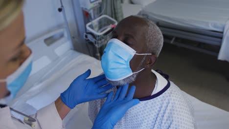 Caucasian-female-doctor-examining-throat-of-african-american-senior-male-patient-wearing-face-mask