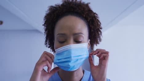 Portrait-of-mixed-race-female-doctor-putting-face-mask-on
