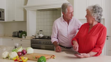Happy-caucasian-senior-couple-in-kitchen-using-tablet-for-recipe-before-preparing-meal