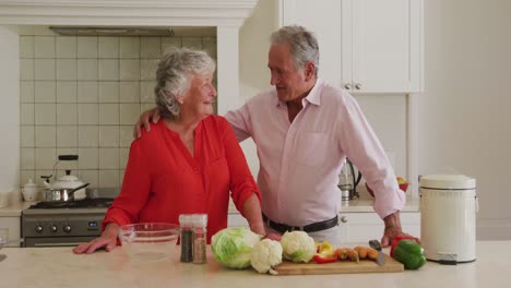 Portrait-of-caucasian-senior-couple-embracing-each-other-in-the-kitchen-at-home
