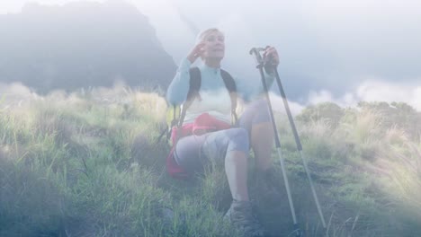 Happy-caucasian-senior-woman-resting-while-hiking-in-mountains,-over-fast-moving-clouds