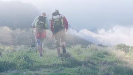 Happy-caucasian-senior-couple-hiking-in-mountains-over-fast-moving-clouds