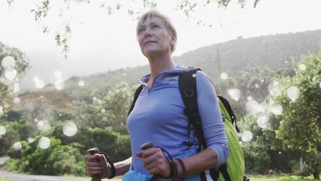 Animation-of-white-spots-over-senior-caucasian-woman-hiking-in-mountains
