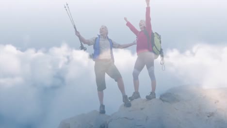 Happy-caucasian-senior-couple-on-top-of-mountains-over-fast-moving-clouds