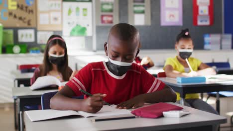 Afroamerikanischer-Junge-Trägt-Gesichtsmaske,-Während-Er-In-Der-Klasse-In-Der-Schule-Lernt
