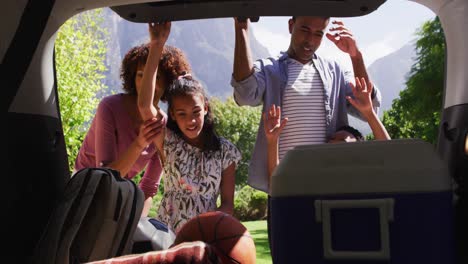Happy-african-american-parents,son-and-daughter,-openieng-car-trunk-with-picninc-supplies