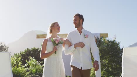 Portrait-of-happy-caucasian-newly-wed-couple,-walking-down-the-altar-outdoors