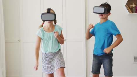 Caucasian-brother-and-sister-gesturing-while-wearing-vr-headset-at-home