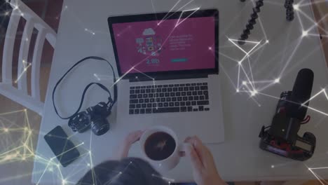 Animation-of-network-of-connections-over-female-vlogger-drinking-coffee-using-laptop-at-home