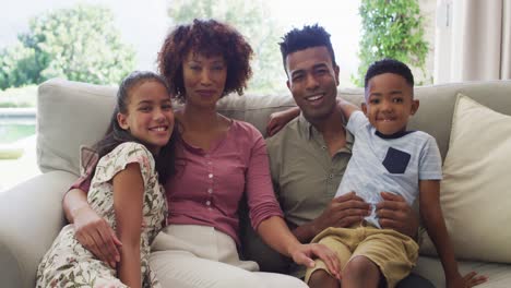 Portrait-of-happy-african-american-parents-with-son-and-daughter,-sitting-on-sofa-at-home