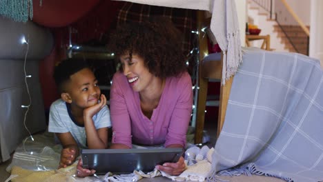 Glückliche-Afroamerikanische-Mutter-Und-Sohn-Liegen-Im-Haus-Aus-Decken-Und-Benutzen-Ein-Tablet