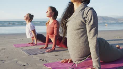 Gruppe-Verschiedener-Freundinnen,-Die-Yoga-Praktizieren-Und-Sich-Am-Strand-Dehnen