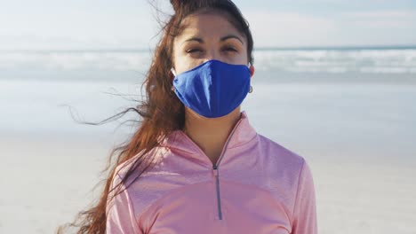 Portrait-of-mixed-race-woman-wearing-face-mask-at-the-beach