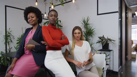 Portrait-of-three-diverse-female-office-colleagues-smiling-at-office