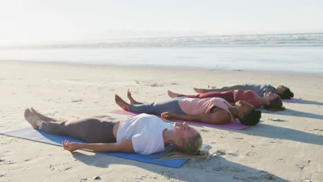 Gruppe-Verschiedener-Freundinnen,-Die-Yoga-Praktizieren-Und-Auf-Matten-Am-Strand-Liegen