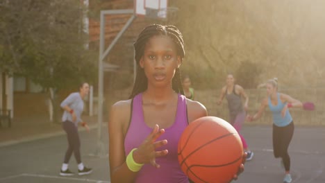 Porträt-Einer-Afroamerikanischen-Basketballspielerin,-Die-Den-Ball-Hält-Und-In-Die-Kamera-Blickt