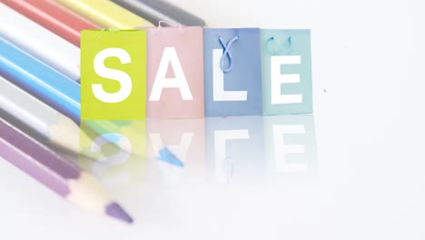 Animation-of-sale-text-on-multi-coloured-shopping-bags-and-colour-pencils-on-white-background