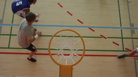 Overhead-view-of-african-american-male-basketball-player-scoring-goal-against-diverse-players