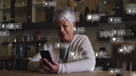 Animation-Von-Social-Media-Symbolen-Und-Zahlen-Auf-Bannern-über-Einer-älteren-Frau,-Die-Ihr-Smartphone-Nutzt