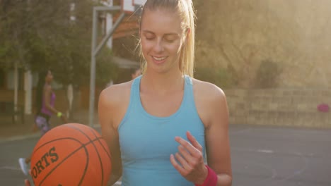 Portrait-of-caucasian-female-basketball-player-holding-ball-and-looking-at-camera