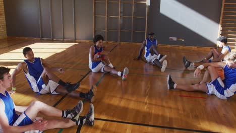 Vielfältiges-Männliches-Basketballteam,-Das-Blaue-Sportkleidung-Trägt-Und-Sich-Dehnt