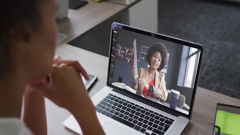 African-american-woman-having-a-video-call-on-laptop-with-female-colleague-at-office