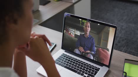African-american-woman-having-a-video-call-on-laptop-with-male-colleague-at-office