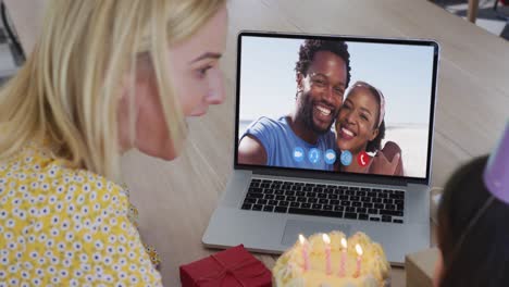 Caucasian-mother-and-daughter-celebrating-birthday-on-video-call-on-laptop-at-home