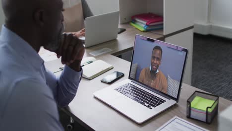 Afroamerikanischer-älterer-Mann,-Der-Einen-Videoanruf-Auf-Dem-Laptop-Mit-Einem-Männlichen-Bürokollegen-Im-Büro-Führt