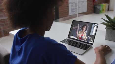 African-american-woman-talking-on-video-call-with-female-colleague-on-laptop-at-office