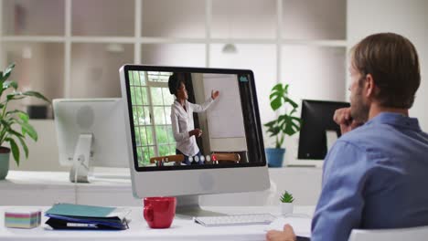 Caucasian-man-having-a-video-call-with-female-colleague-on-laptop-at-office