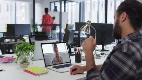Middle-eastern-man-having-a-video-call-with-female-colleague-on-laptop-at-office