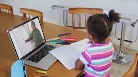 Afroamerikanisches-Mädchen-Macht-Hausaufgaben,-Während-Sie-Zu-Hause-Einen-Videoanruf-Mit-Einem-Männlichen-Lehrer-Auf-Dem-Laptop-Führt