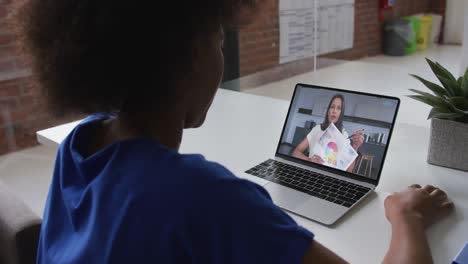 African-american-woman-talking-on-video-call-with-female-colleague-on-laptop-at-office