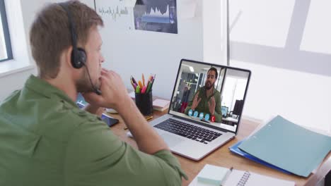Kaukasischer-Mann-Mit-Telefon-Headset,-Der-Im-Büro-Einen-Videoanruf-Mit-Einem-Männlichen-Kollegen-Auf-Einem-Laptop-Führt