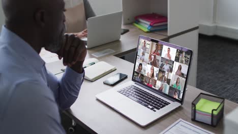 African-american-senior-man-having-a-video-conference-with-colleagues-on-laptop-at-office