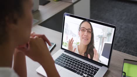 Mid-section-of-african-american-woman-having-a-video-call-on-laptop-with-female-colleague-at-office