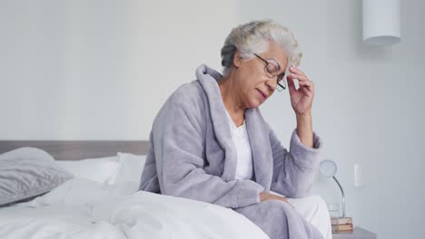Stressed-african-american-senior-woman-sitting-on-the-bed-at-home